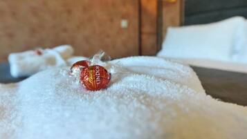 Een bed met een witte deken en een Lindor chocolade.