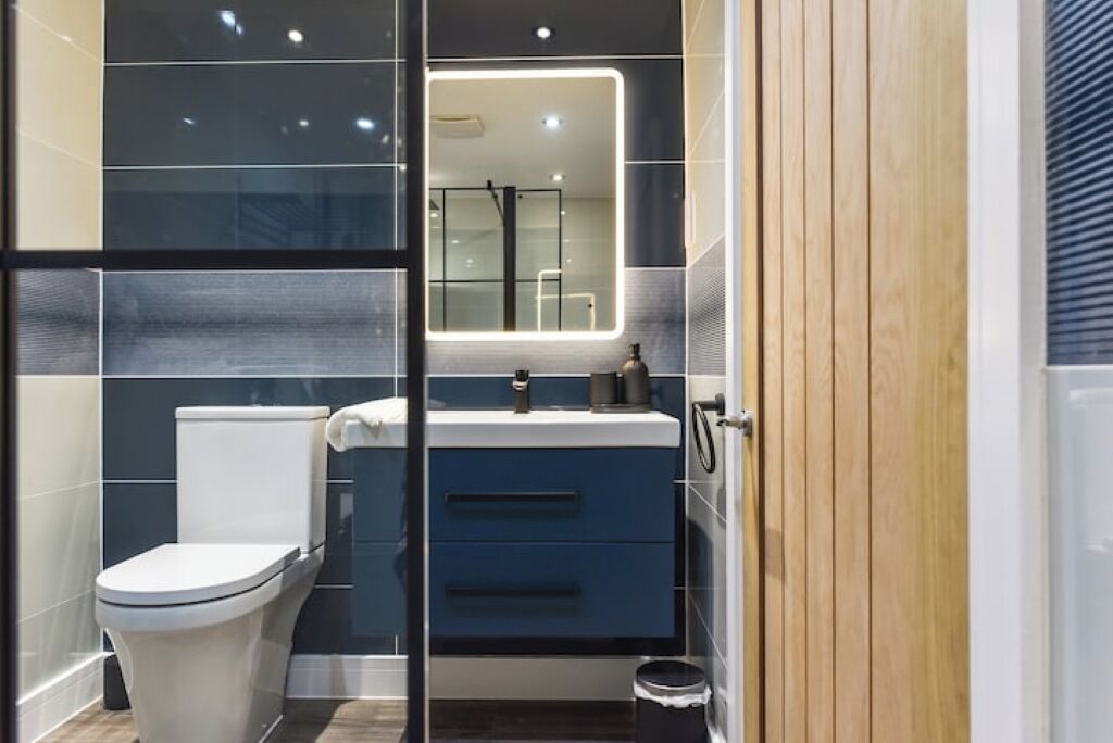 A modern bathroom with a toilet, sink, and mirror.