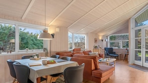 A spacious living area with a dining table, sofas, and a large window offering a view of greenery. - "Nashota" - 600m from the sea by Interhome (Væggerløse)