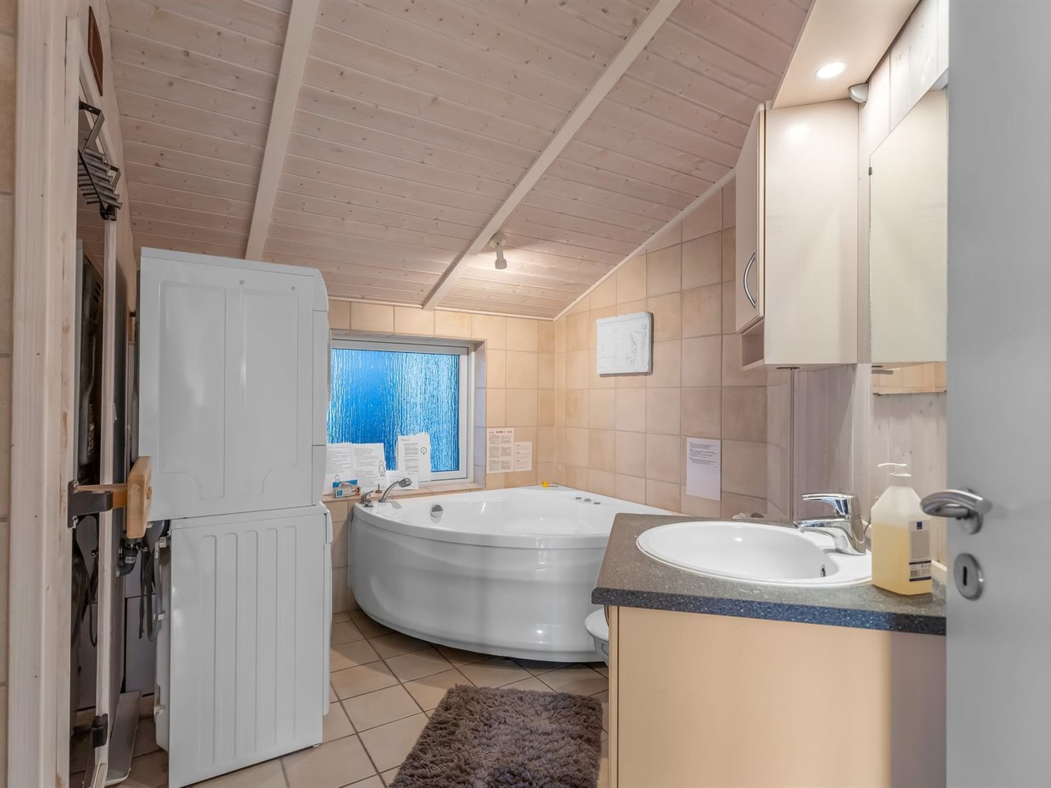 A modern bathroom with a freestanding bathtub, a sink, and a window with a view.