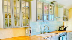 A kitchen with grey cabinets, a wooden countertop, and a tiled backsplash.