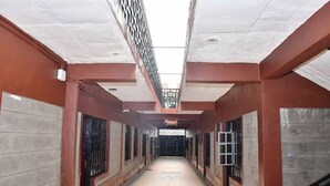 Un couloir avec un plafond haut, des murs en béton et des garde-corps en métal.