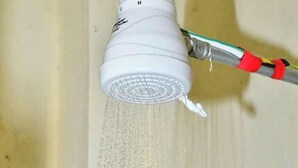 Un objet blanc muni d’un filtre en treillis, vraisemblablement un filtre à eau, fixé à un tuyau métallique par un connecteur rouge et vert.