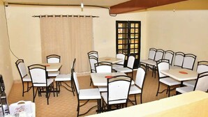 Un espace repas comprenant plusieurs tables et chaises, un rideau et une fenêtre donnant sur un paysage agréable.