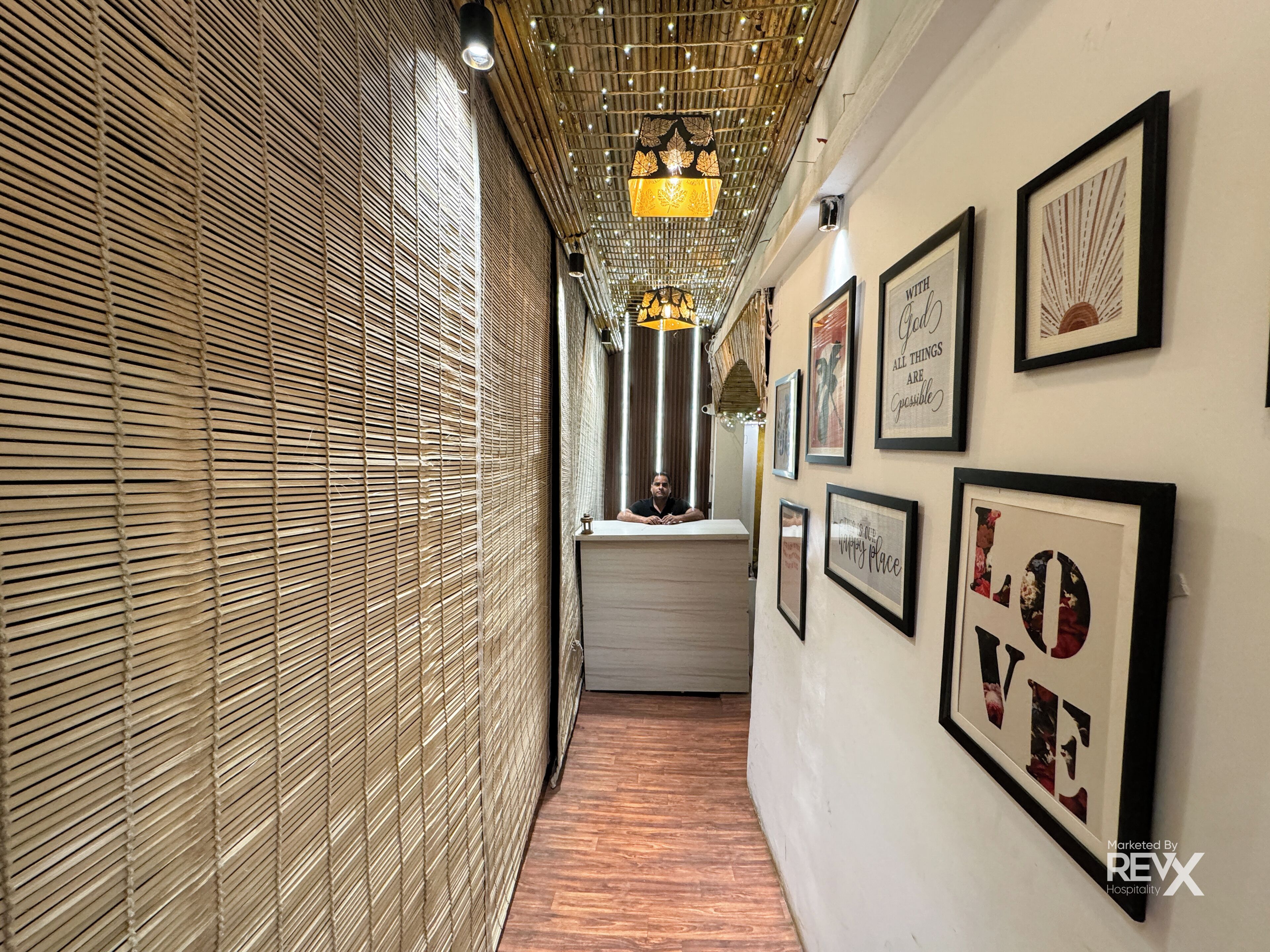 A corridor with bamboo blinds, framed inspirational quotes, and a wooden floor.