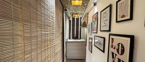 A corridor with bamboo blinds, framed inspirational quotes, and a wooden floor.