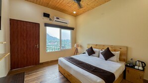 Une chambre d’hôtel avec un plafond en bois, un grand lit avec des oreillers, une table de chevet avec une bouilloire et une fenêtre donnant sur un pont et des collines.