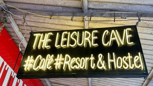 Une enseigne au néon faisant la publicité de «The Leisure Cave » en tant que café, centre de villégiature et auberge de jeunesse.