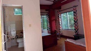 Una habitación con cama, ventilador de techo, ventana con cortinas y vista al exterior.