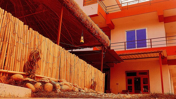 Un edificio con techo de paja, un balcón y una ventana con contraventanas azules.