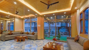 A spacious living room with a wooden ceiling, large windows, and a patterned floor. - Hotel Divine Paradise Manali (Manali)