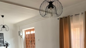 Ein Wohnzimmer mit zwei grünen Sofas, einem Holzesstisch und einer hängenden schwarzen Leuchte.