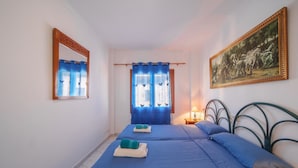 Een kamer met twee bedden, een spiegel, een schilderij en een raam met gordijnen.