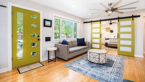 A room with a green door, a sofa, a coffee table, and a large window. - Backyard Wonderland: Ultimate Outdoor Fun (Denver)