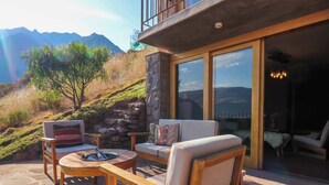 A patio with wooden furniture, a stone wall, and a view of mountains. - w* | Splendid 3BR House in Valle Sagrado (Urubamba)