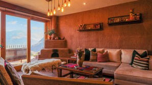 A cozy living room with a sofa, coffee table, and a large window offering a mountain view. - w* | Splendid 3BR House in Valle Sagrado (Urubamba)