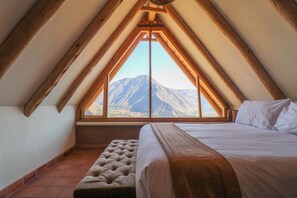 Un dormitorio con un ventanal grande, una cama y un banco.