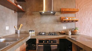 A kitchen with a stainless steel sink, a gas stove, and wooden cabinets. - w* | Splendid 3BR House in Valle Sagrado (Urubamba)