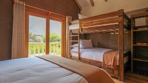 Une chambre dotée d’un grand lit, d’un lit superposé et d’un balcon avec une rambarde en bois.