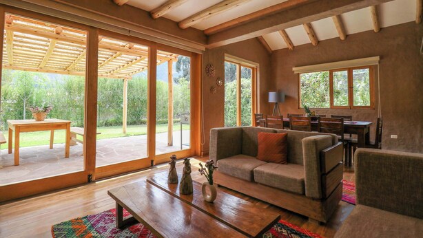 Un salon spacieux avec un plafond en bois, de grandes fenêtres, un canapé et une table basse.