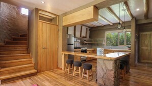 Une cuisine moderne avec des plans de travail en bois, un îlot central doté de tabourets et un four encastré.