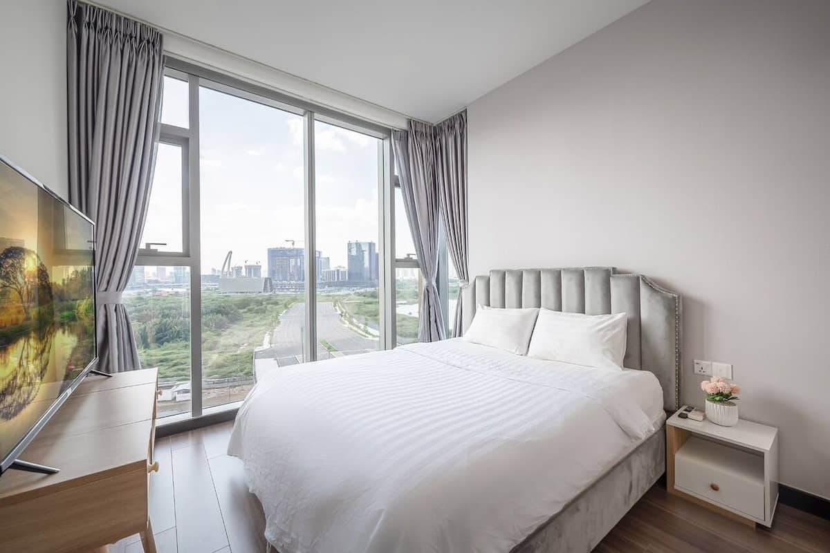 Un dormitorio moderno con una cama grande, televisión y vistas a la ciudad.