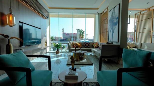 A modern living room with a sofa, two armchairs, a coffee table, and a TV. There are plants and decorative items on the coffee table. - Arjan Park Hotel Wadi Ad Dawasir (Wadi-Ad-Dawasir)