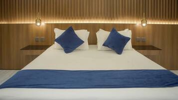 A modern hotel room with a large bed, two bedside tables, and a wooden wall paneling.