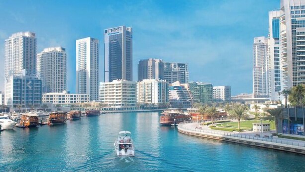 A city skyline with high-rise buildings, a marina with boats, and a waterfront promenade. - 1 BR in Marina (Dubai)