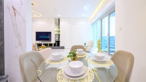 A modern dining area with a glass table set for four, surrounded by comfortable chairs. A flat-screen TV is mounted on the wall in the background. - 1 BR in Marina (Dubai)