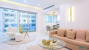 A modern living room with a glass coffee table, a beige sofa, and a white armchair. - 1 BR in Marina (Dubai)