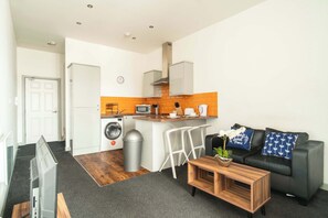 Cozy living space with a kitchenette, sofa, and flat-screen TV.