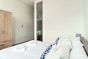 Relax in a serene space with a comfortable bed, wardrobe, and wall-mounted TV.
