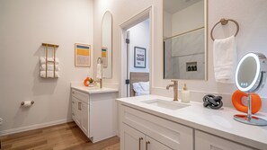 Un baño moderno con muebles blancos, un espejo grande y un tocador con doble lavabo.