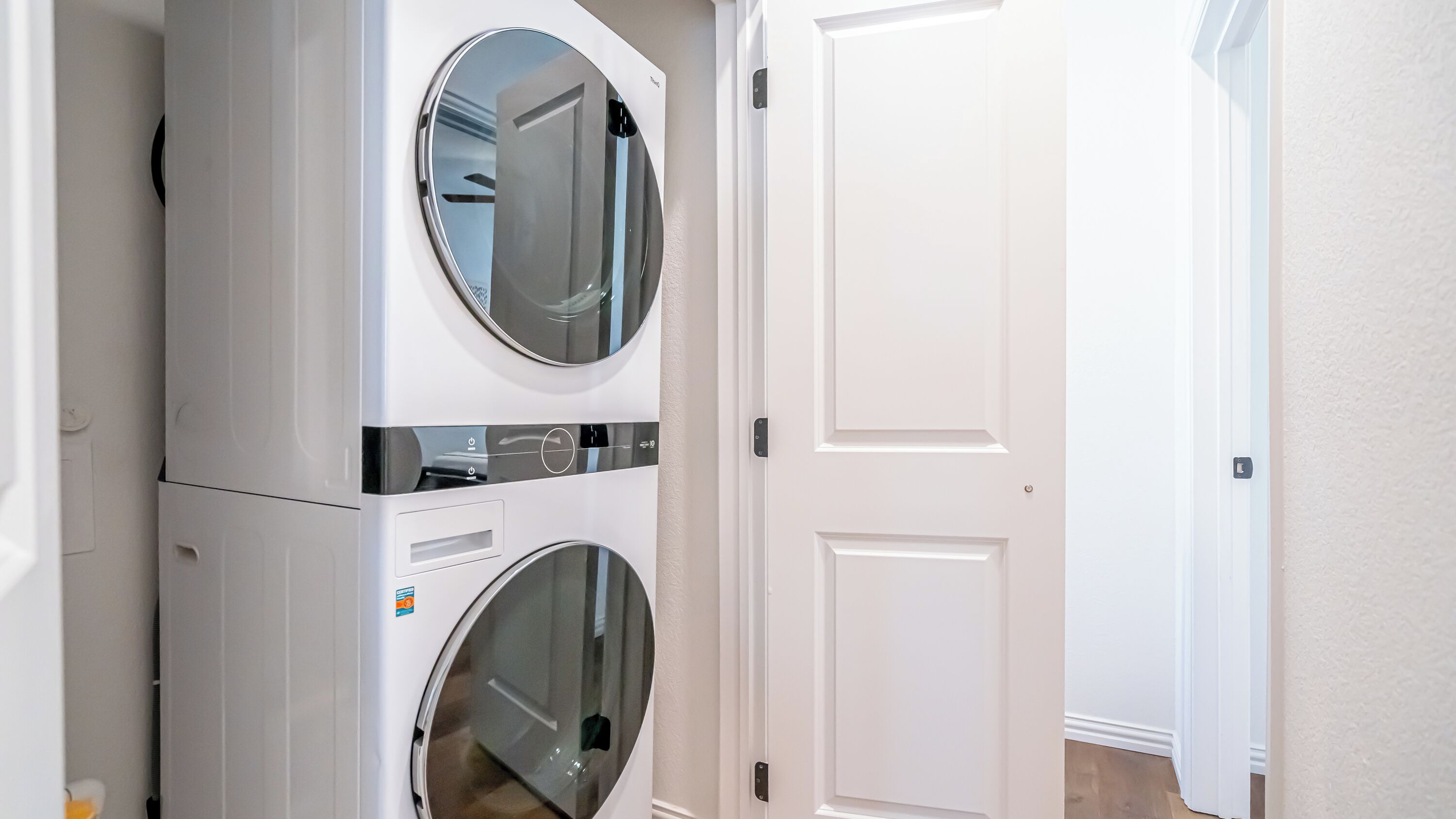 A laundry room with two stacked front-loading washing machines and a closed door in the background.