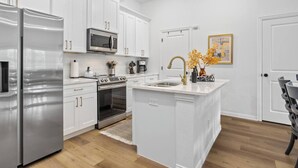 Una cocina moderna con armarios blancos, electrodomésticos de acero inoxidable y una isla central con fregadero.