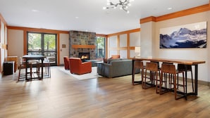 A spacious living area with a stone fireplace, wooden flooring, and a large window. - Foxtail Flat | Capitol Peak Lodge #3219 | 1B/1B (Snowmass Village)