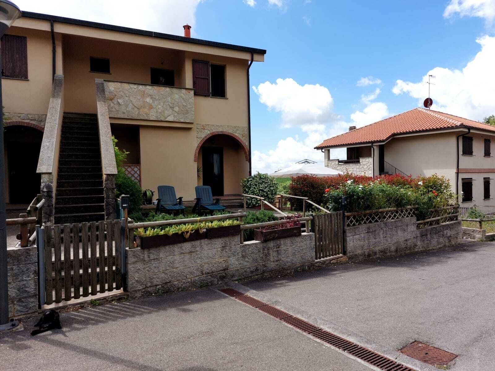 Ein zweistöckiges Gebäude mit Steinverkleidung, einem Balkon und einem kleinen Garten mit Sitzgelegenheiten.