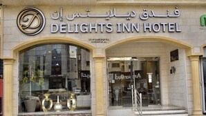 DELIGHTS INN -hotellin sisäänkäynti, jossa on suuret lasi-ikkunat ja marmorista julkisivu.