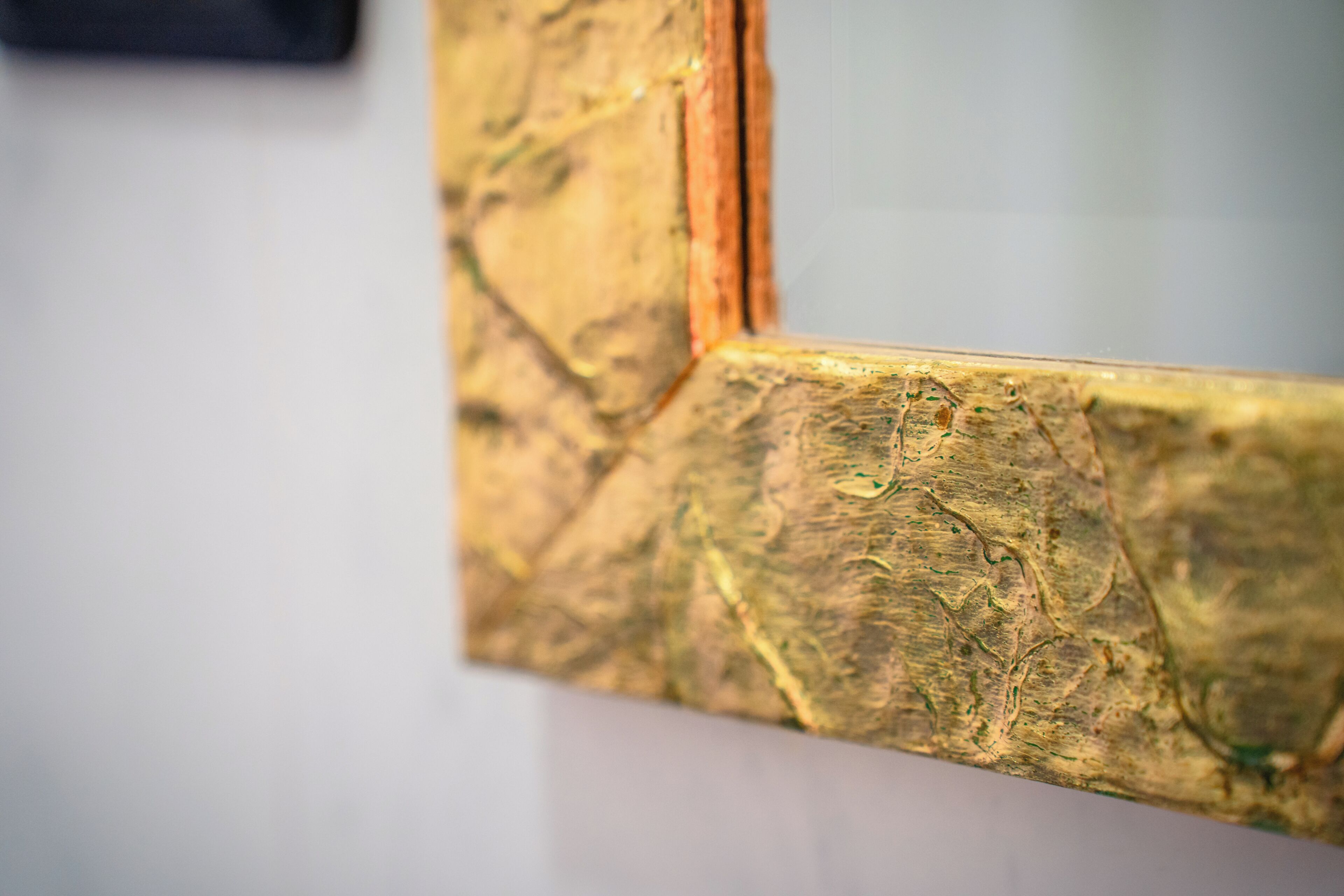 A close-up of a textured, gold-colored frame with visible wear and tear.