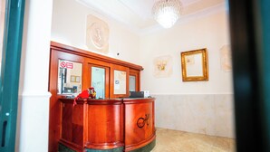Un área de recepción con un mostrador de madera, una araña de cristal y obras de arte enmarcadas en las paredes.