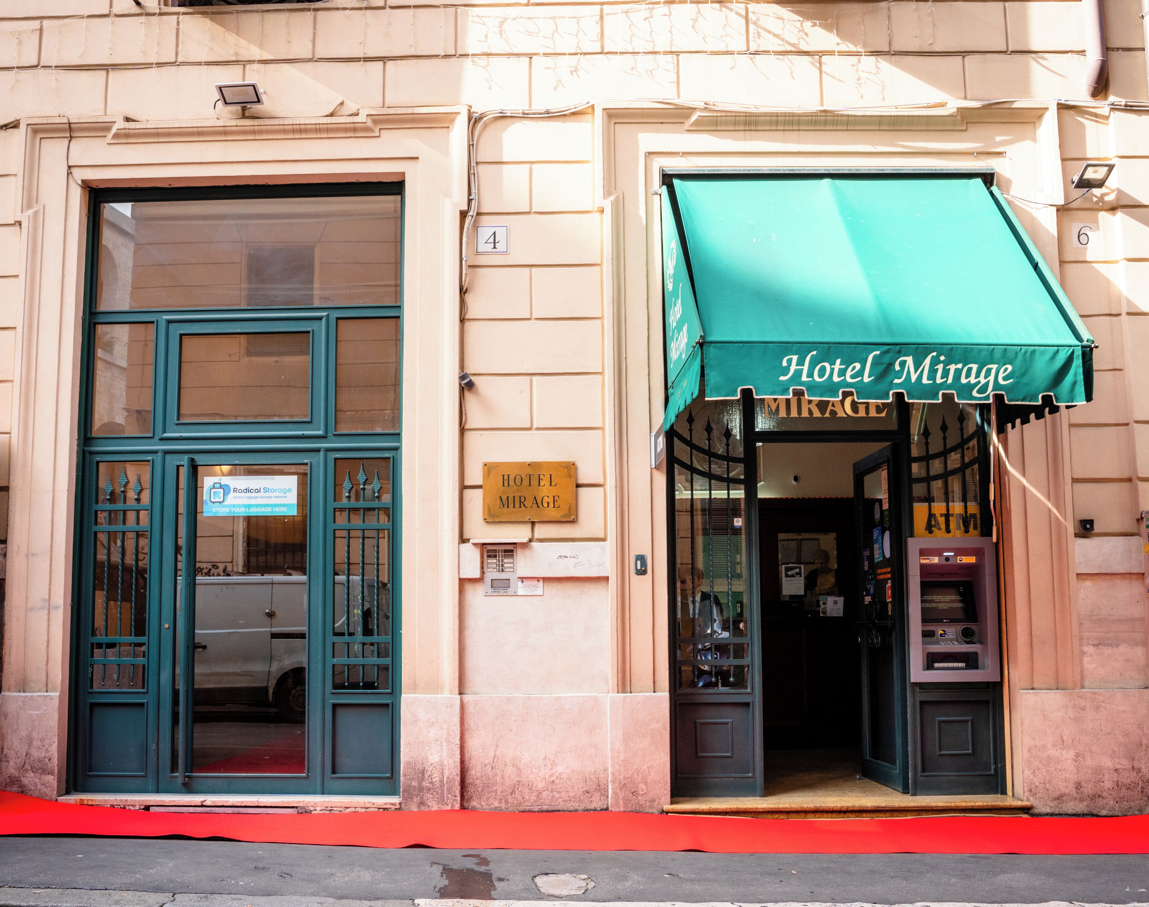 A hotel entrance with a green awning, a sign indicating 'Hotel Mirage', and a visible ATM machine.