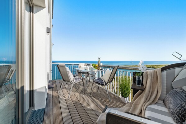 Enjoy breathtaking sea views from this balcony with a table and chairs.