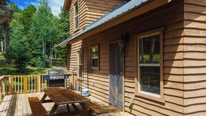 A wooden cabin with a deck, a grill, and a picnic table.