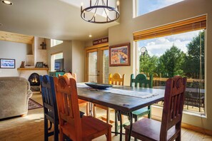 A dining area with a wooden table and chairs, a fireplace, and a view of the outdoors.