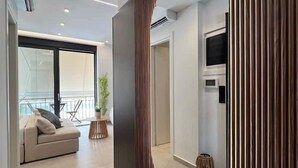 A modern living room with a large mirror, a sofa, and a TV. - BlueMotion - PortSuite (Piraeus)