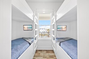 Un dormitorio con dos camas, una ventana y vistas a una casa.