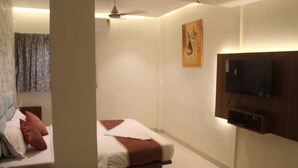 Een hotelkamer met twee bedden, een flatscreen televisie aan de wand en een plafondventilator.