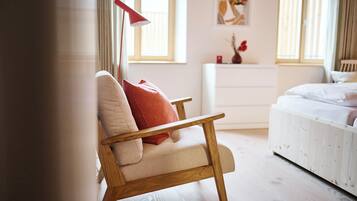 A bedroom with a wooden chair, a bed, a nightstand, and a red floor lamp.