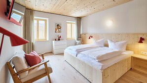 Un dormitorio con paneles de madera, una cama, mesitas de noche, una silla y un escritorio.
